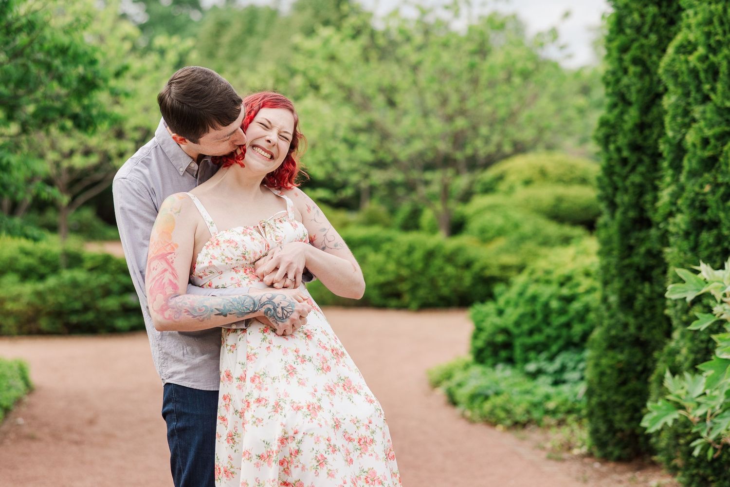 A couple shares a romantic moment in a blooming garden path with lush green landscaping at Cantigny Park