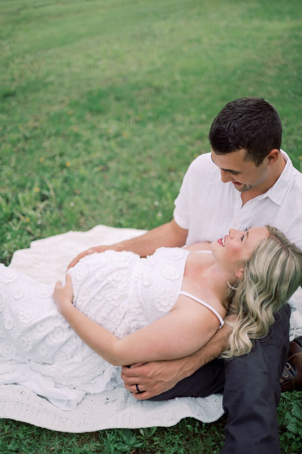 A romantic couple lying on a blanket in the grass during a spring photo session.
