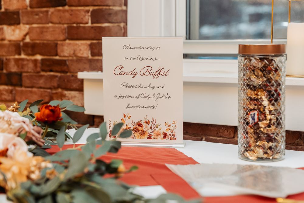Close-up of an elegant wedding table setting with floral decorations and a glass jar filled with mixed nuts.