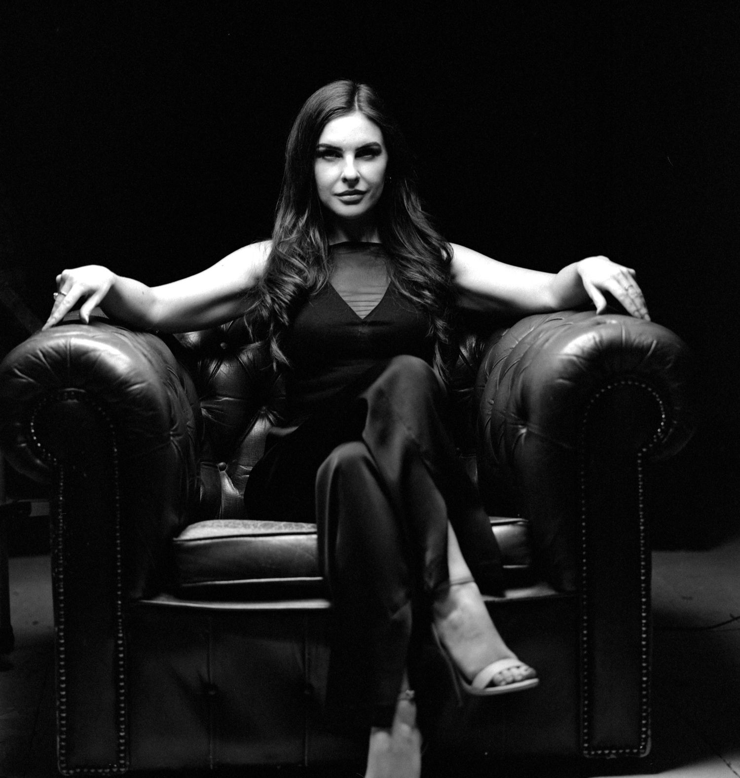 Creative black and white film noir style Portrait Photograph of UK model Alice Bryan in a large leather chair