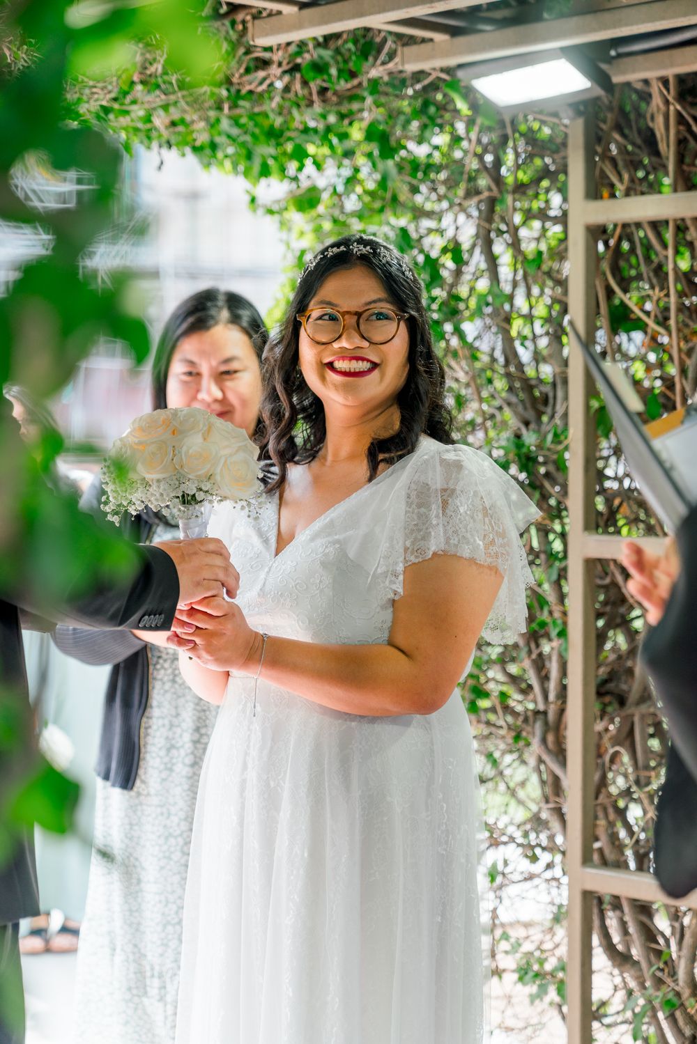 A wedding celebration in a garden setting with natural greenery overhead.