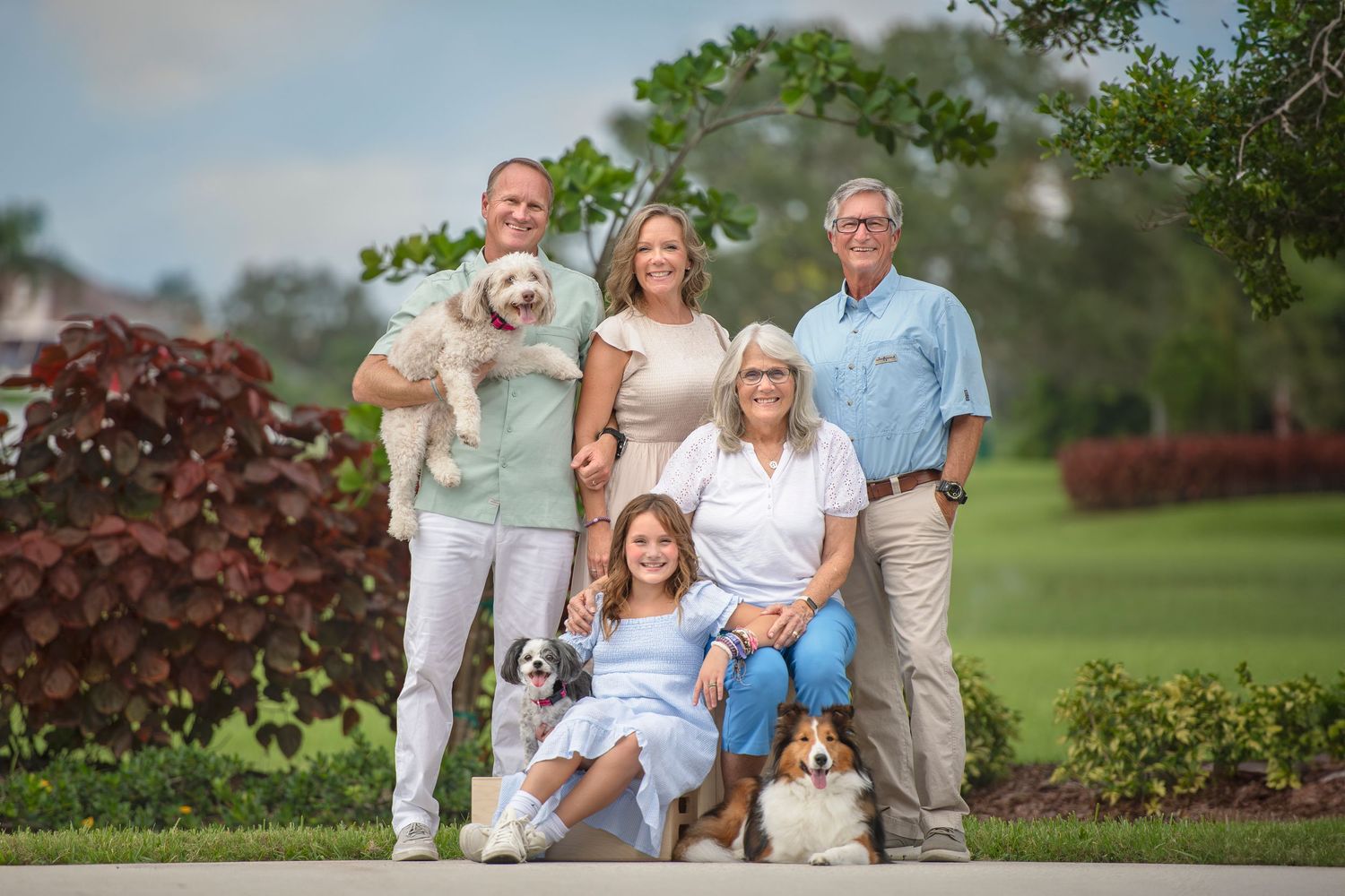 Tortoise Island generational family portraits. Grandma is sitting on the chair and dad is holding a dog. They all wear pastel colour clothes