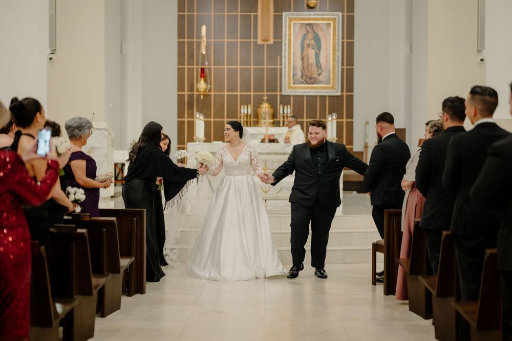 A joyous moment during a wedding ceremony inside a Catholic church as attendees line the pews.