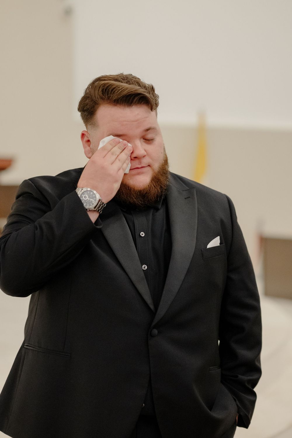 Man in black suit wipes tear from eye during emotional moment showing genuine feelings and reaction.