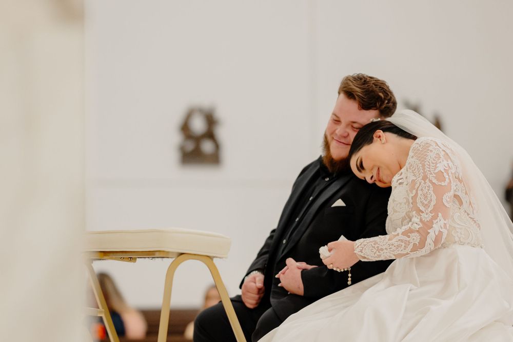 A couple shares an intimate moment of laughter while seated during a wedding ceremony.