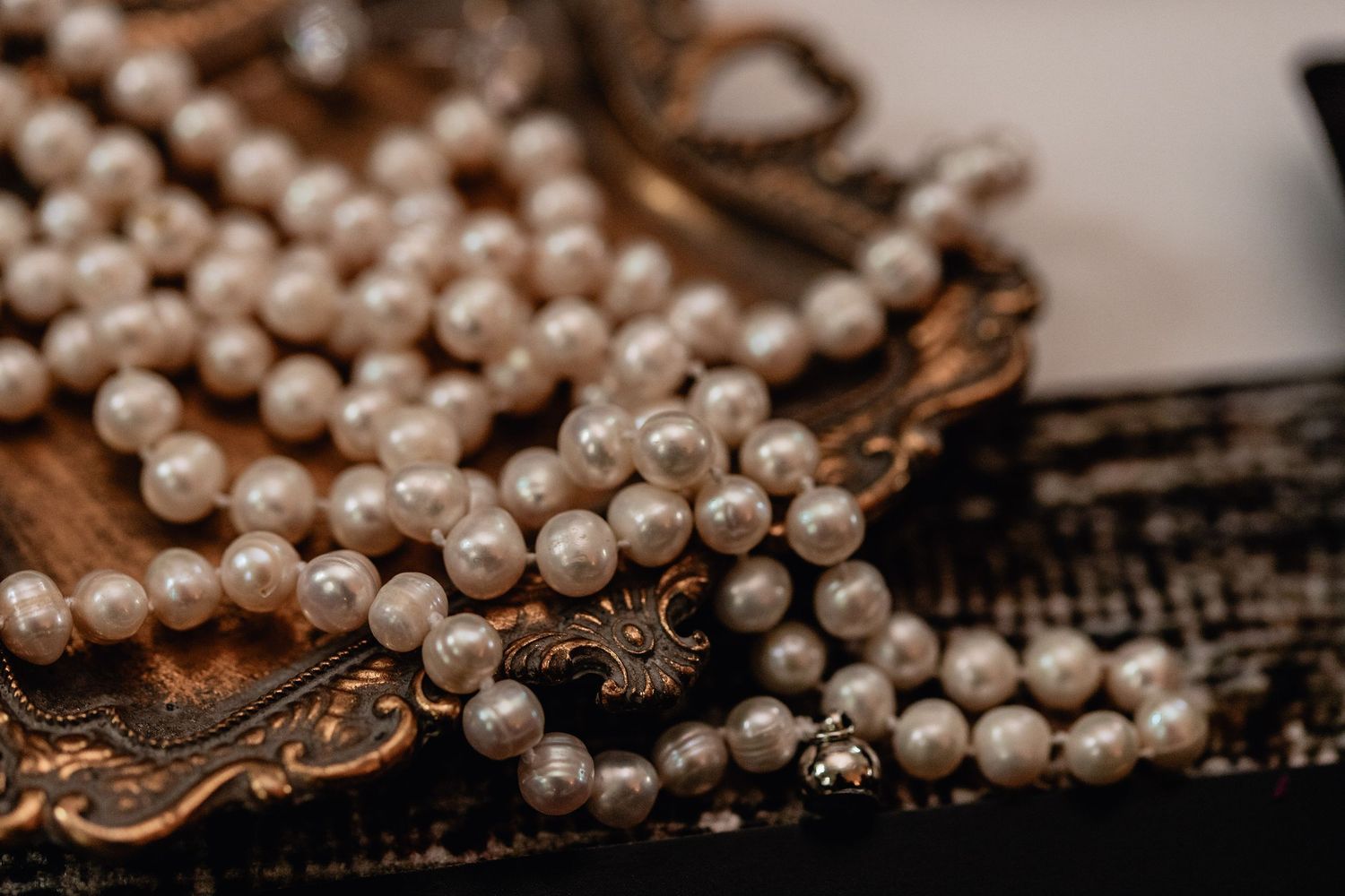 Vintage pearl necklace on ornate gold tray in elegant wedding flat lay, perfect for classic bridal detail and luxury wedding inspiration.
