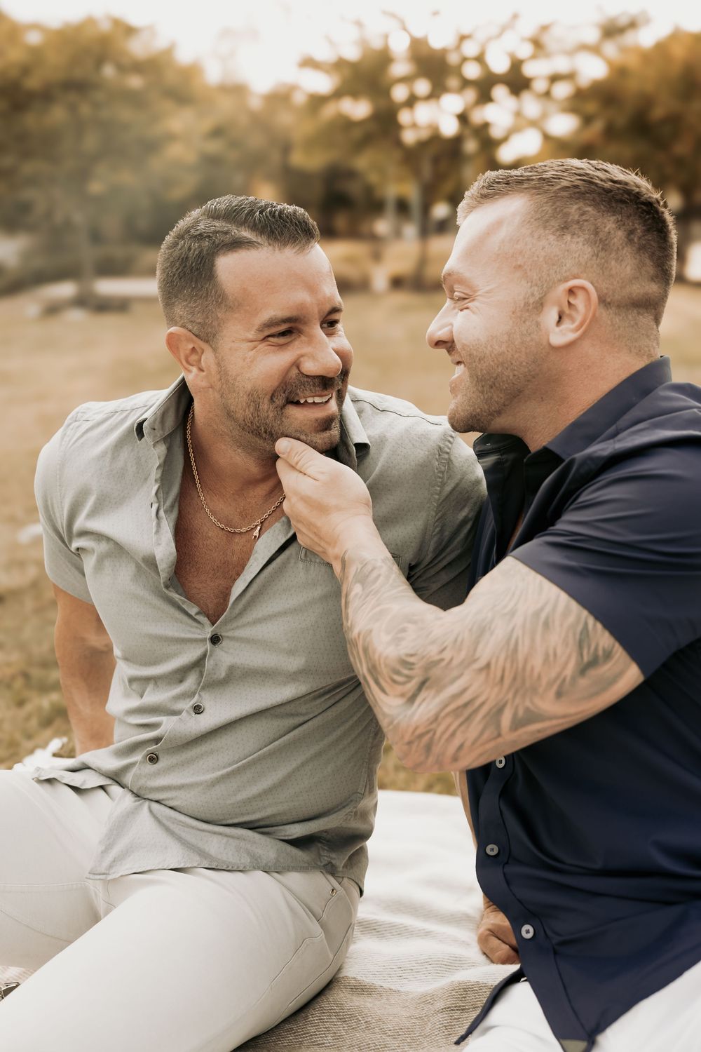 Two people sharing a joyful moment together while sitting outdoors in warm sunlight.