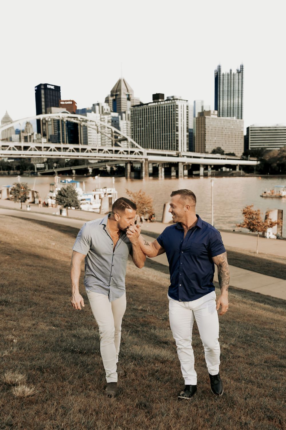 A couple walking and laughing together with Pittsburgh's iconic bridges and skyline in the background.