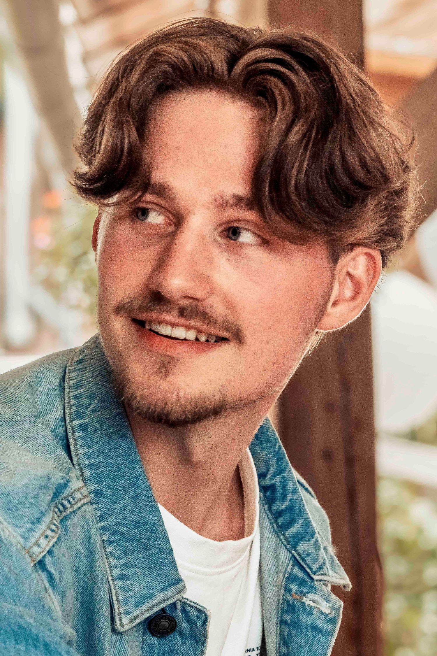 Portrait in denim jacket against wooden background.