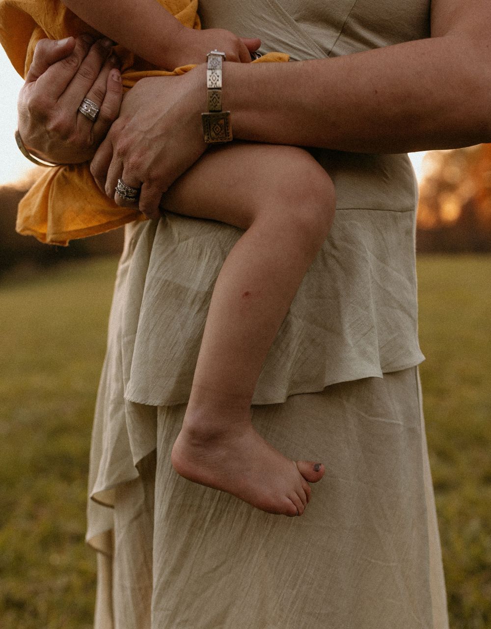 Close-up of bare baby feet and hands with jewelry details.