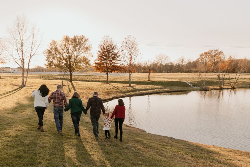 Group walking together along a serene pond on an autumn afternoon.