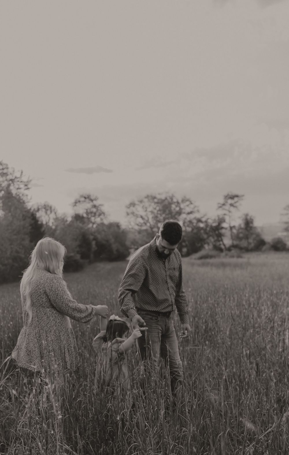A couple and child share a tender moment together in a misty field at dusk.