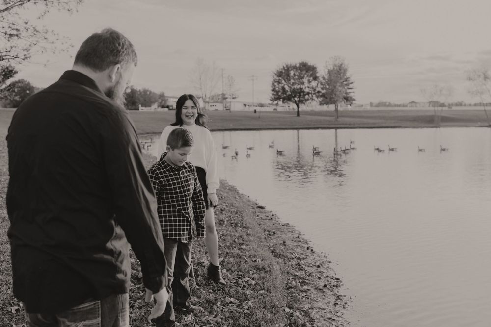 Family watching ducks swim in a pond during an afternoon outing.