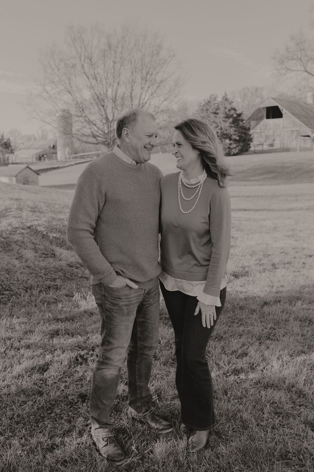 A romantic black and white portrait of a couple sharing a tender moment in a rural setting.