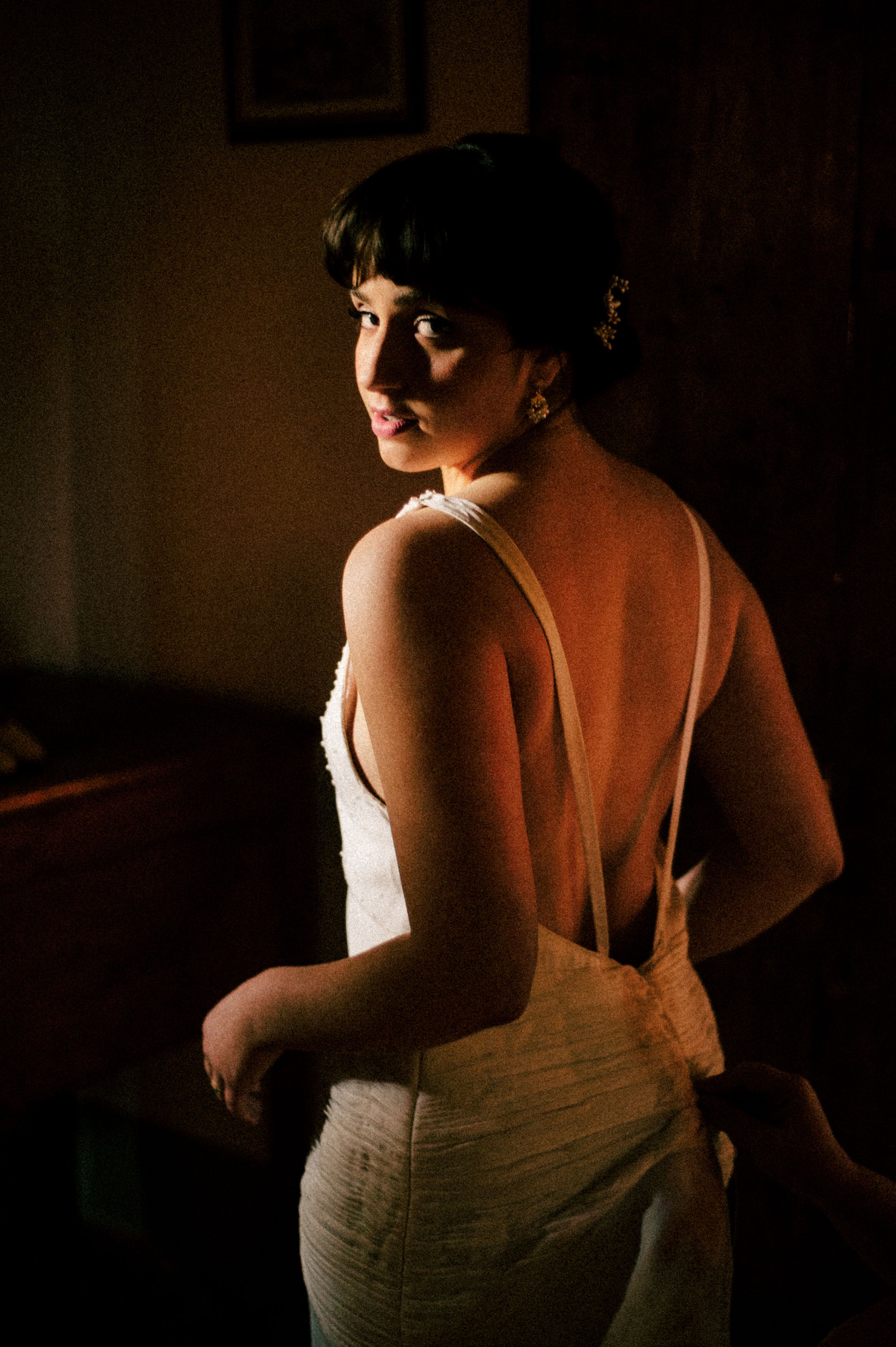 A dramatic backlit portrait of a wedding dress with an elegant open back design.