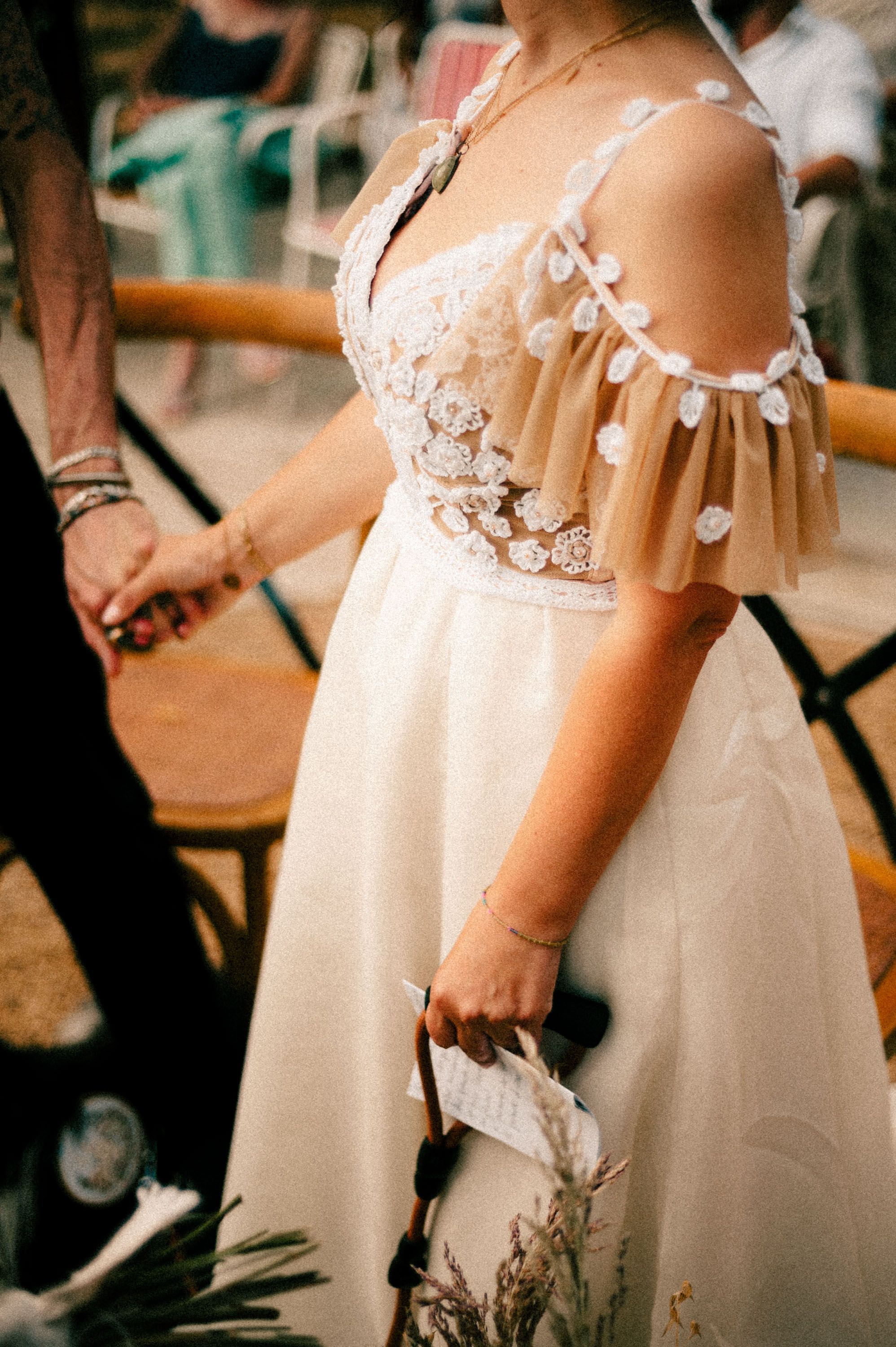 Detail of romantic off-shoulder wedding dress with lace and pom-pom trim.