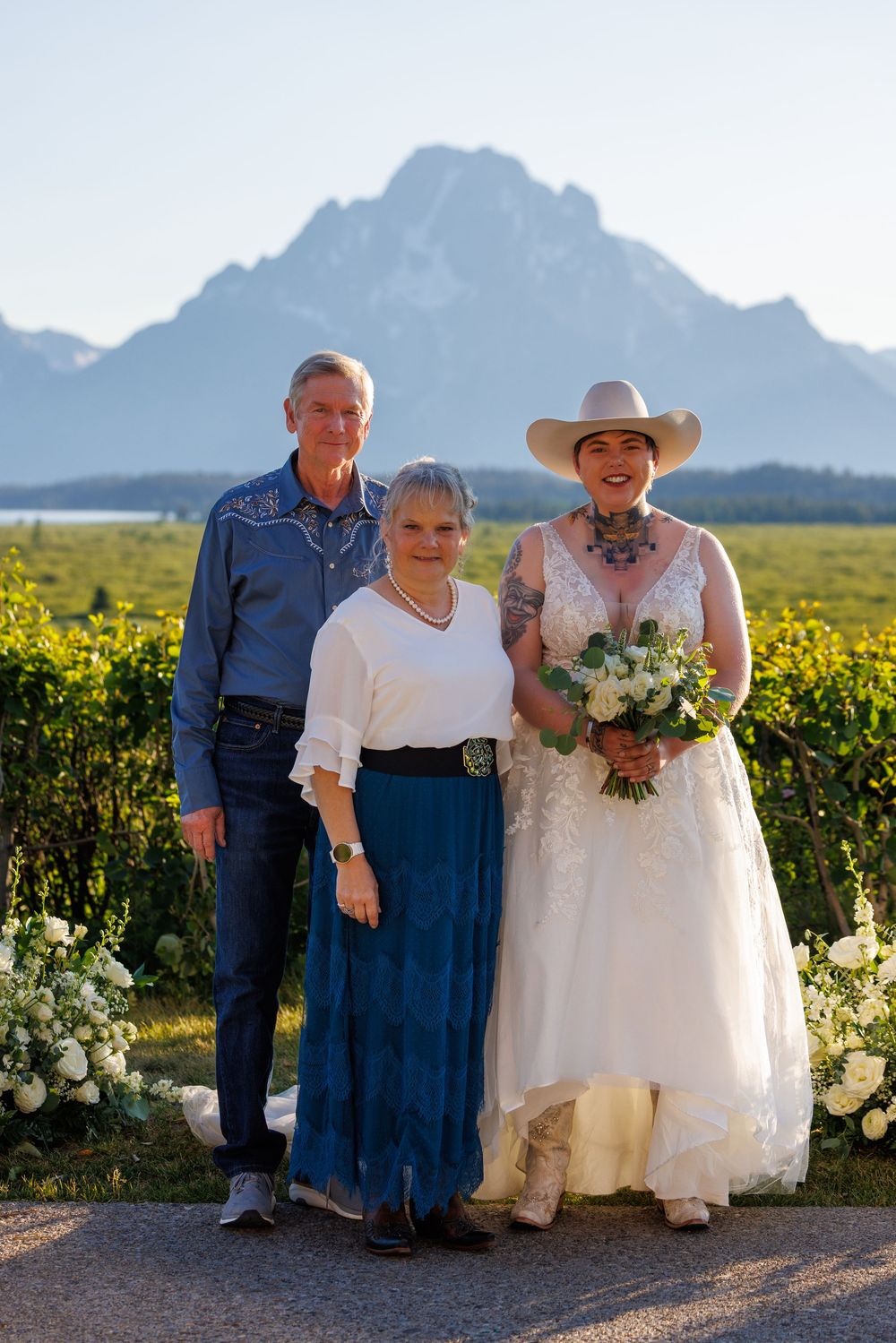A bride poses with family members during a wedding celebration with the Grand Tetons rising majestically in the background.