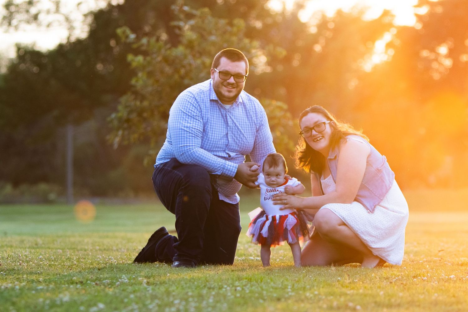 Family sitting together on grass during golden sunset in park.