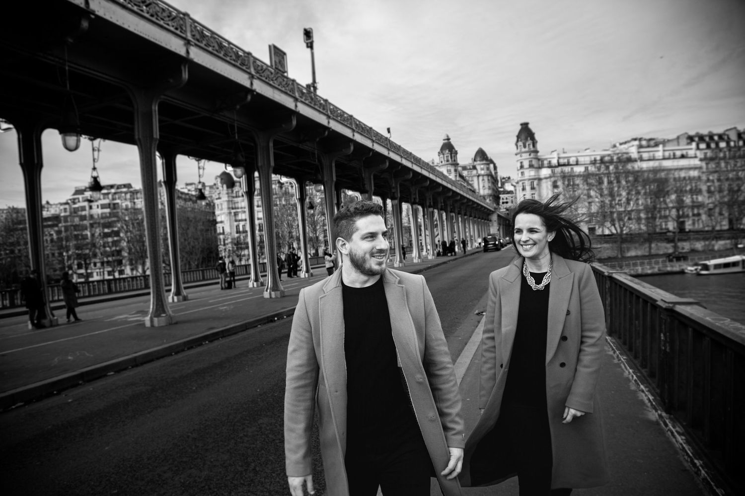 Couple walking along Bir-Hakeim bridge in a black and white urban scene.