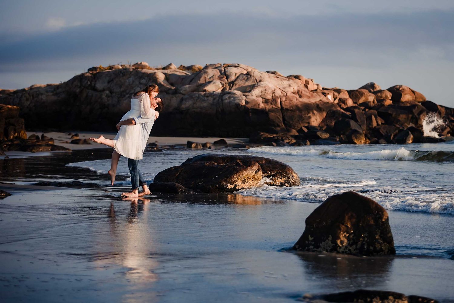 While walking through the gentle surf at Sunrise this couple share a passionate kiss during their engagement Session