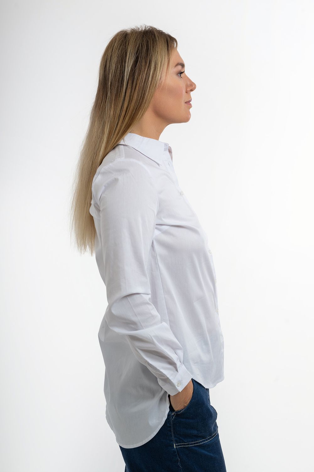 Side profile view of person wearing crisp white button-down shirt and blue jeans against white background.