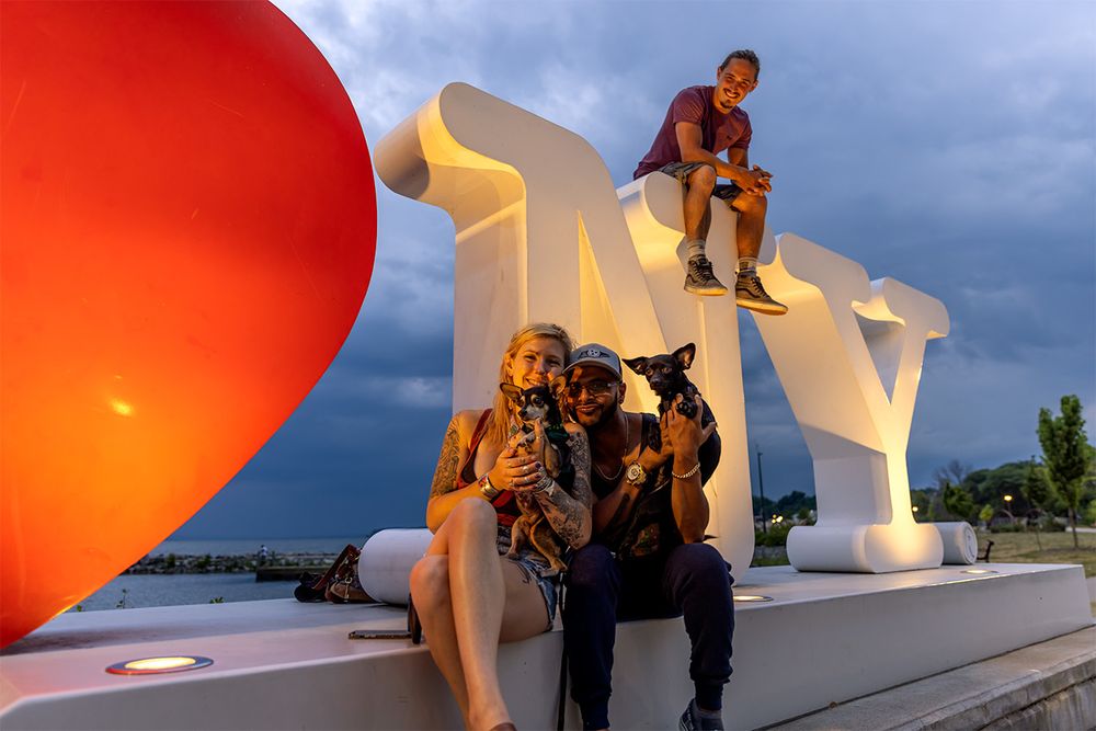 Group enjoying sunset by large white letters with a giant red balloon floating nearby.