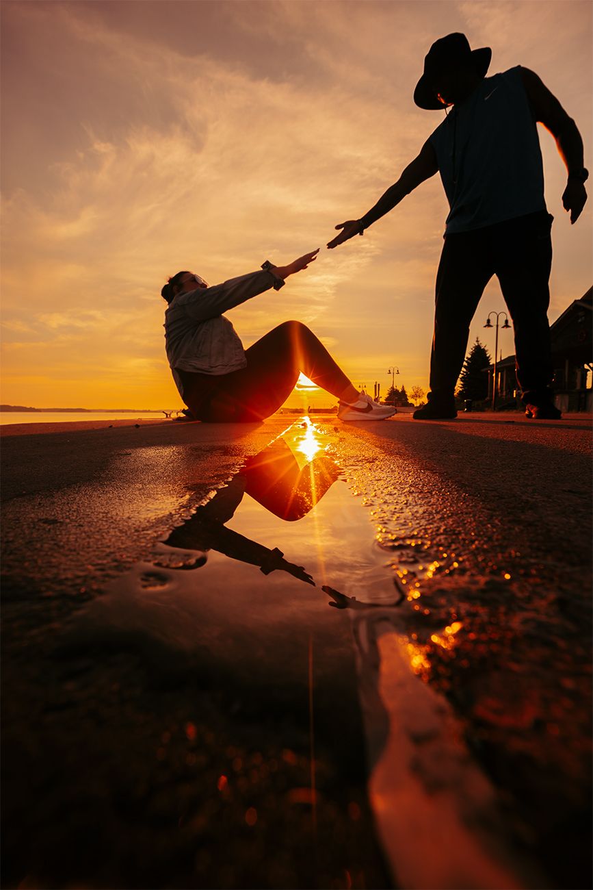 Silhouettes against sunset sky with reflection in wet ground creating dramatic lighting effect.