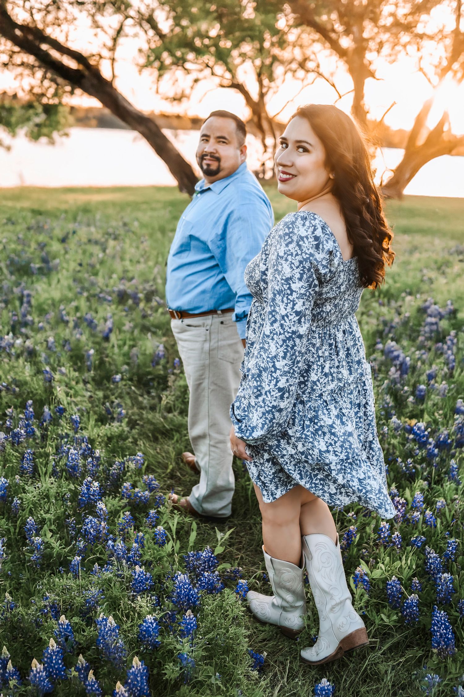 Engagement photo of couple holding hands with bluebonnets stretching out behind them at Ennis Trail