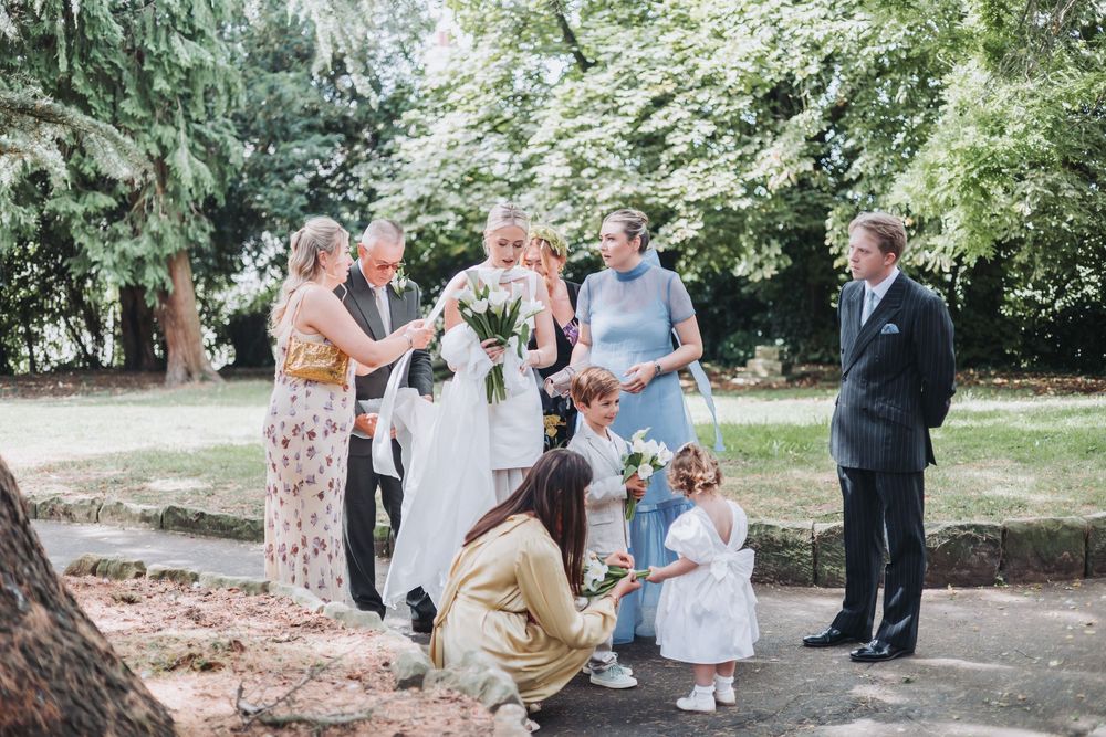 A small group gathers outdoors in a park-like setting for a casual celebration on a sunny day.