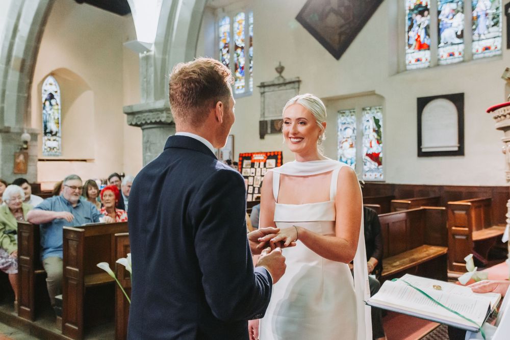A wedding ceremony taking place inside a traditional church with stained glass windows and wooden pews in the background.