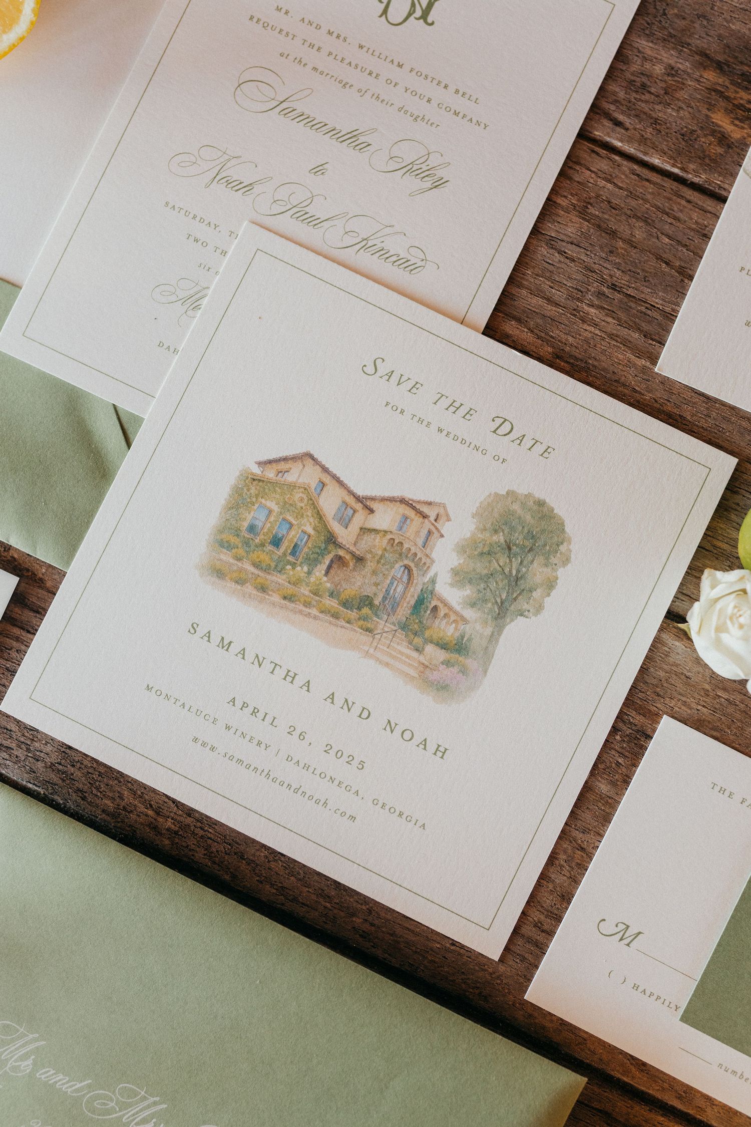 Wedding invitation featuring a delicate watercolor illustration of a rustic house set against green sage-colored envelopes.