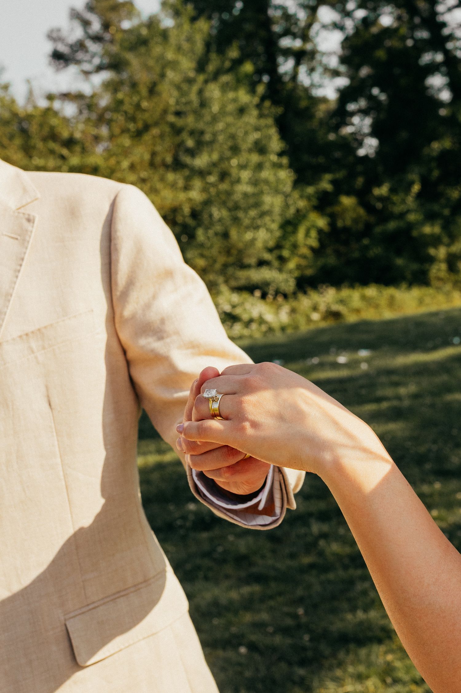 Four sequential close-up images show hands placing and adjusting a ring on a finger in sunlit outdoor setting.