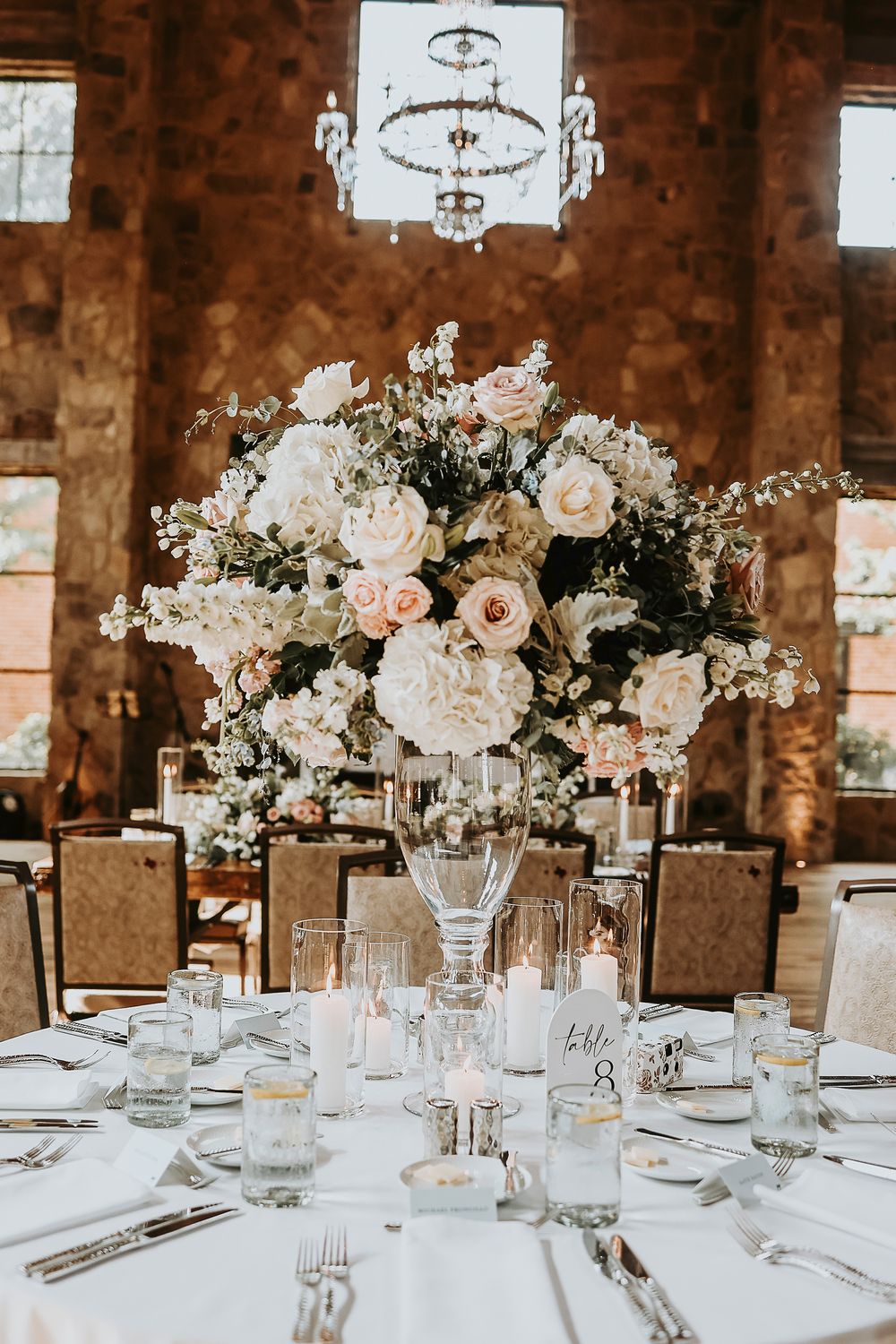 Blush roses, ivory ranunculus, and eucalyptus centerpiece in vintage-style vase