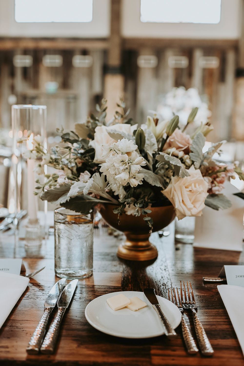 Elegant reception table with blush and ivory floral centerpiece and loose greenery