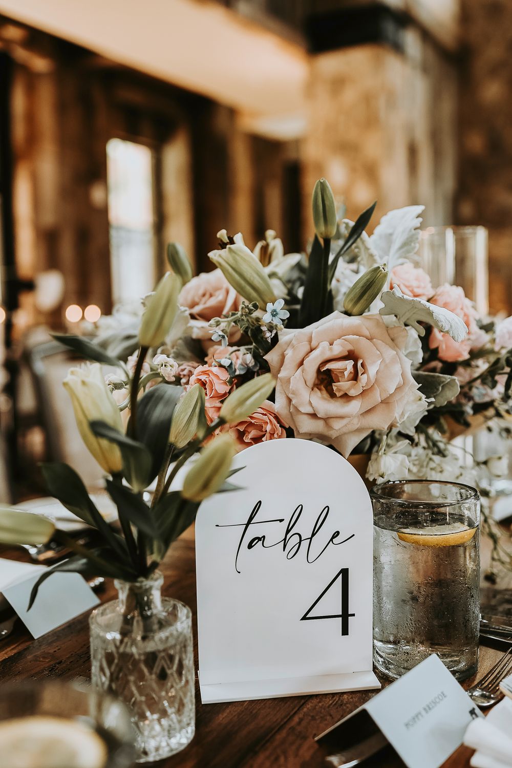Soft blush and ivory floral arrangements on reception tables with glass votives