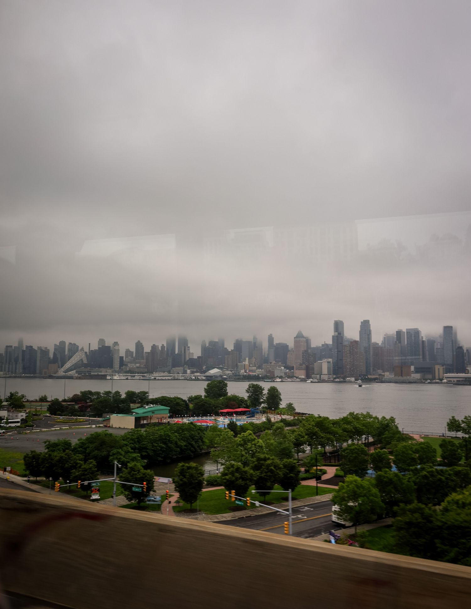 Panoramic cityscape of New York City skyline under overcast skies viewed from Liberty State Park across harbor.