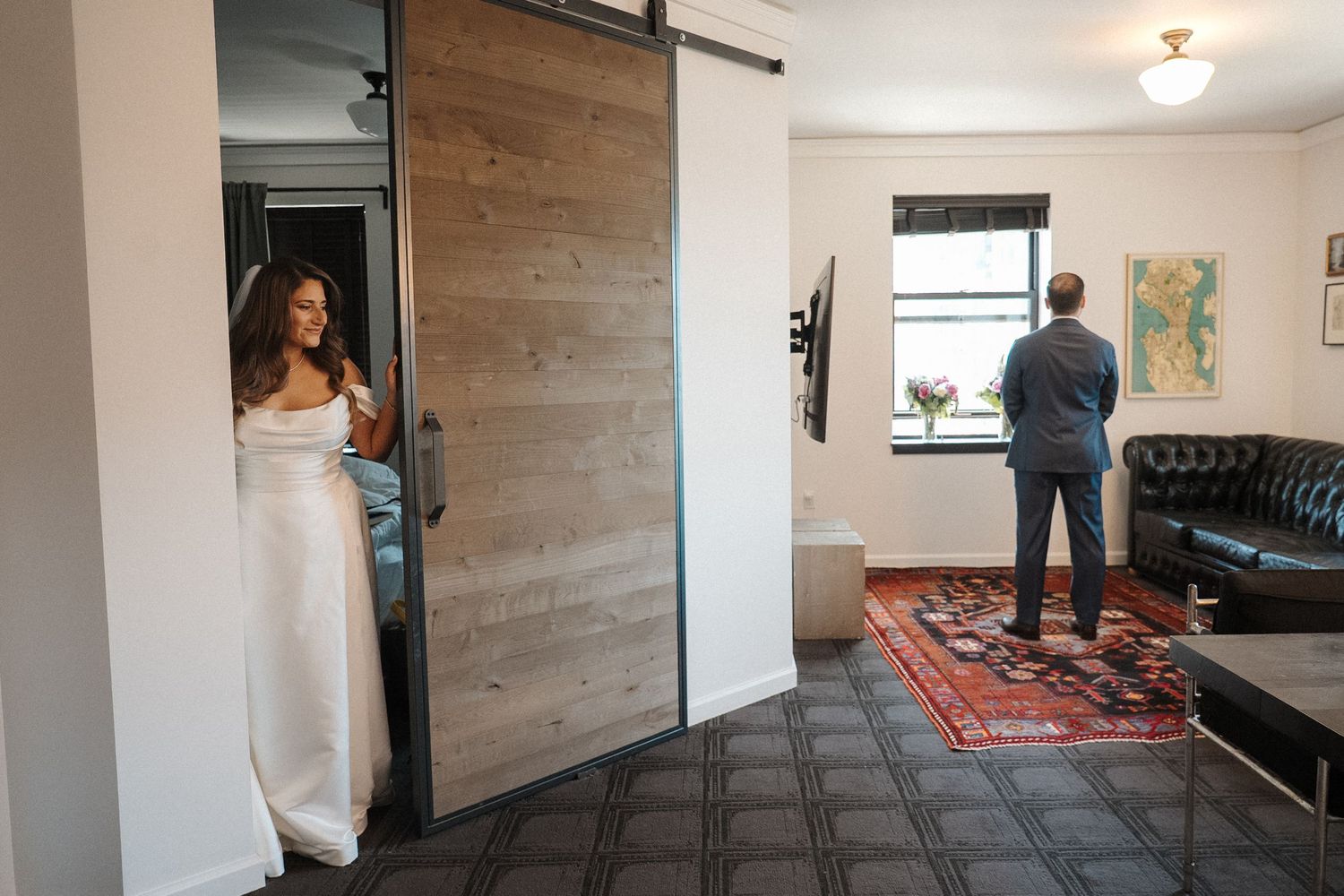 Modern apartment interior with sliding barn door, leather sofa, and decorative red area rug.