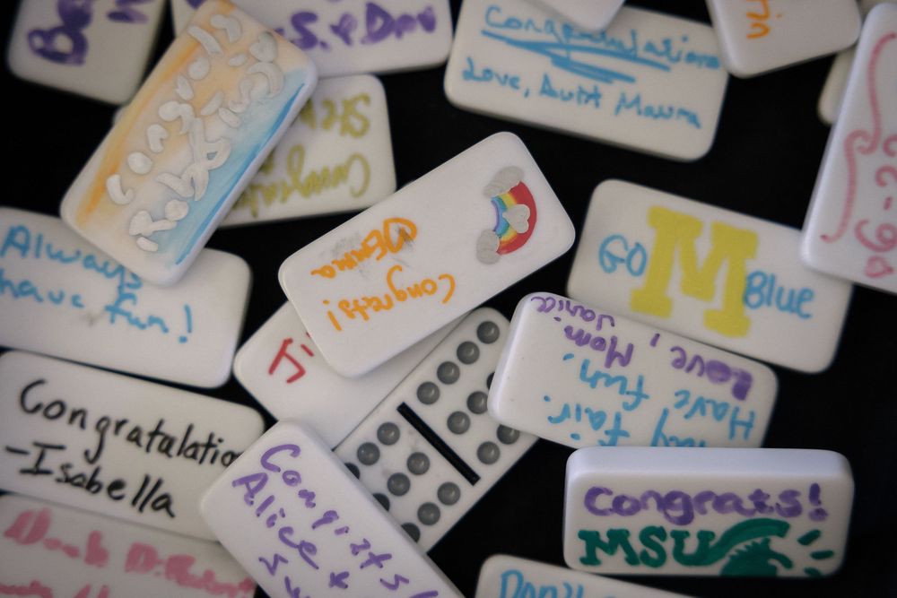 A collection of colorful handwritten name tags and labels spread across a dark surface.