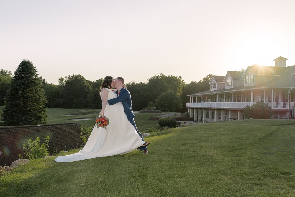 A romantic sunset wedding moment on a sweeping green lawn with an elegant colonial-style building in the background.