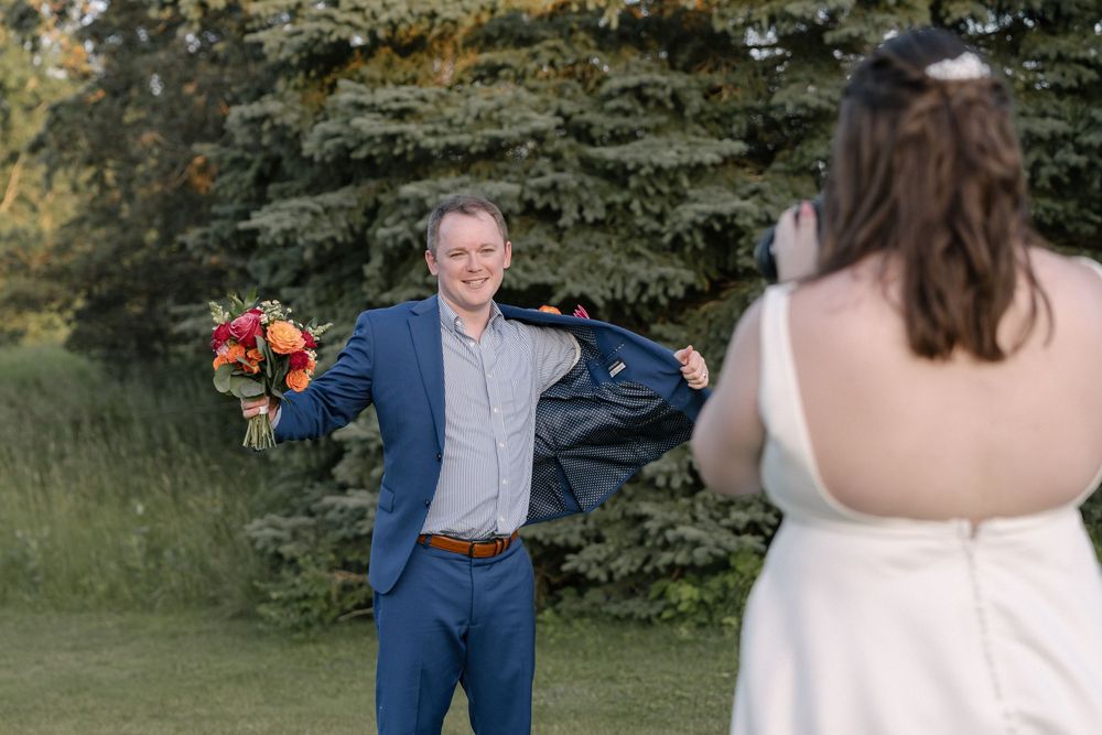 Wedding couple shares playful moments during outdoor portrait session with evergreen trees in background.