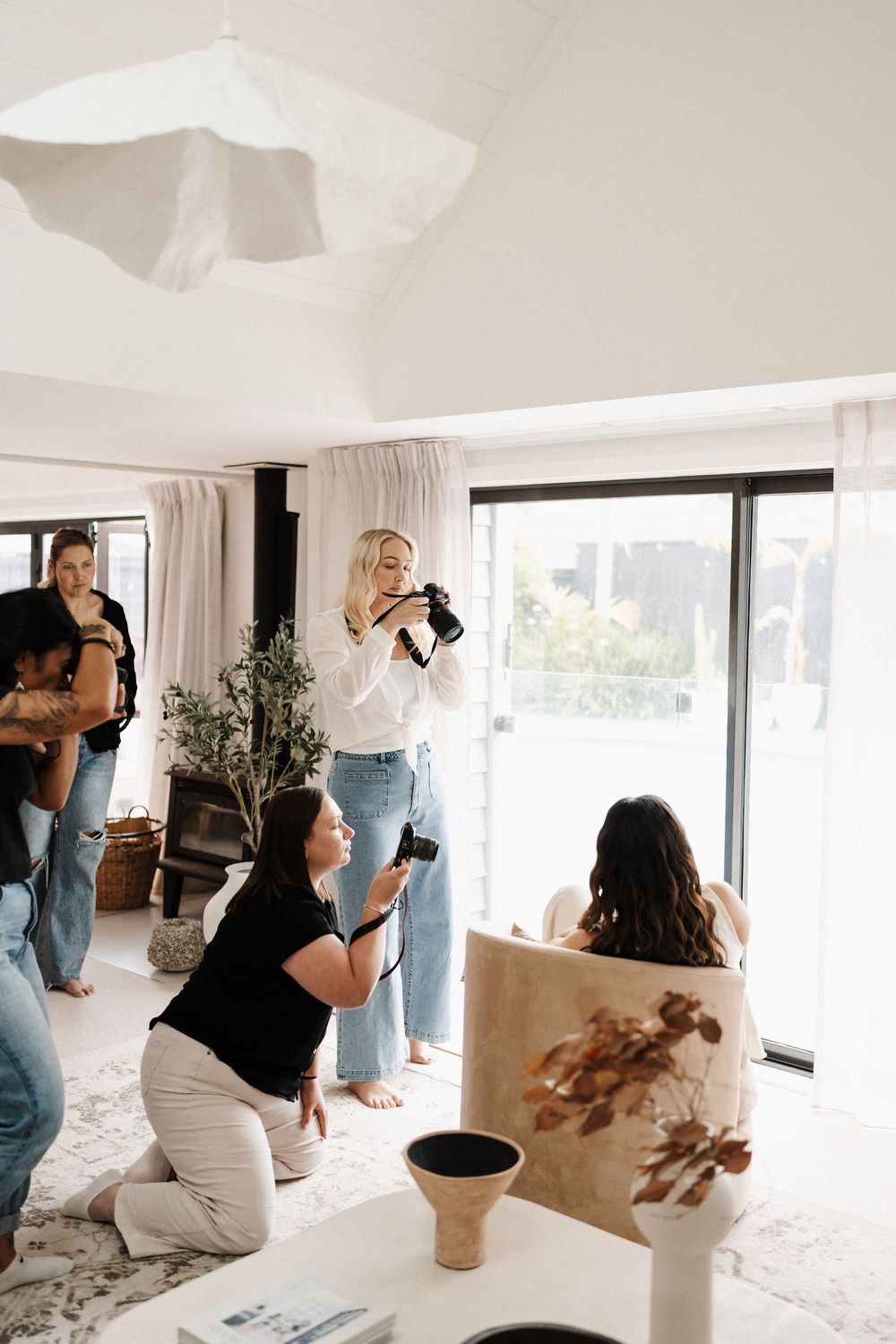 Professional photographers working together in a bright modern studio space capturing content with cameras.