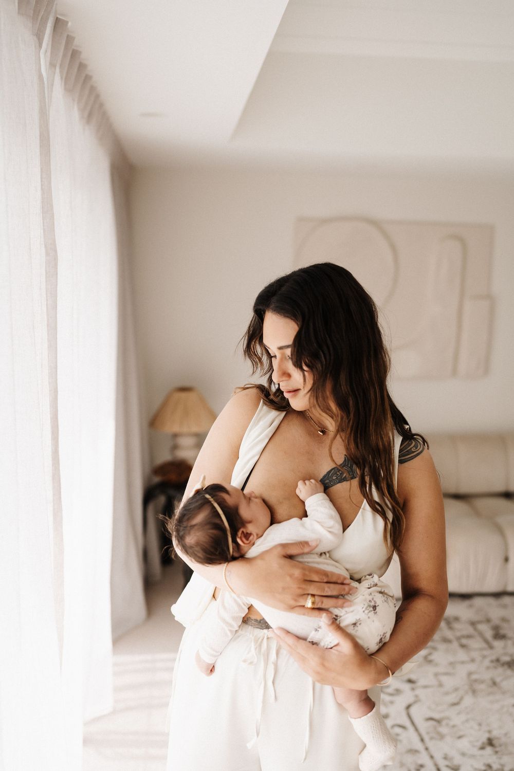 A tender series of intimate black and white photos showing parent and baby bonding together in a soft white bedroom.