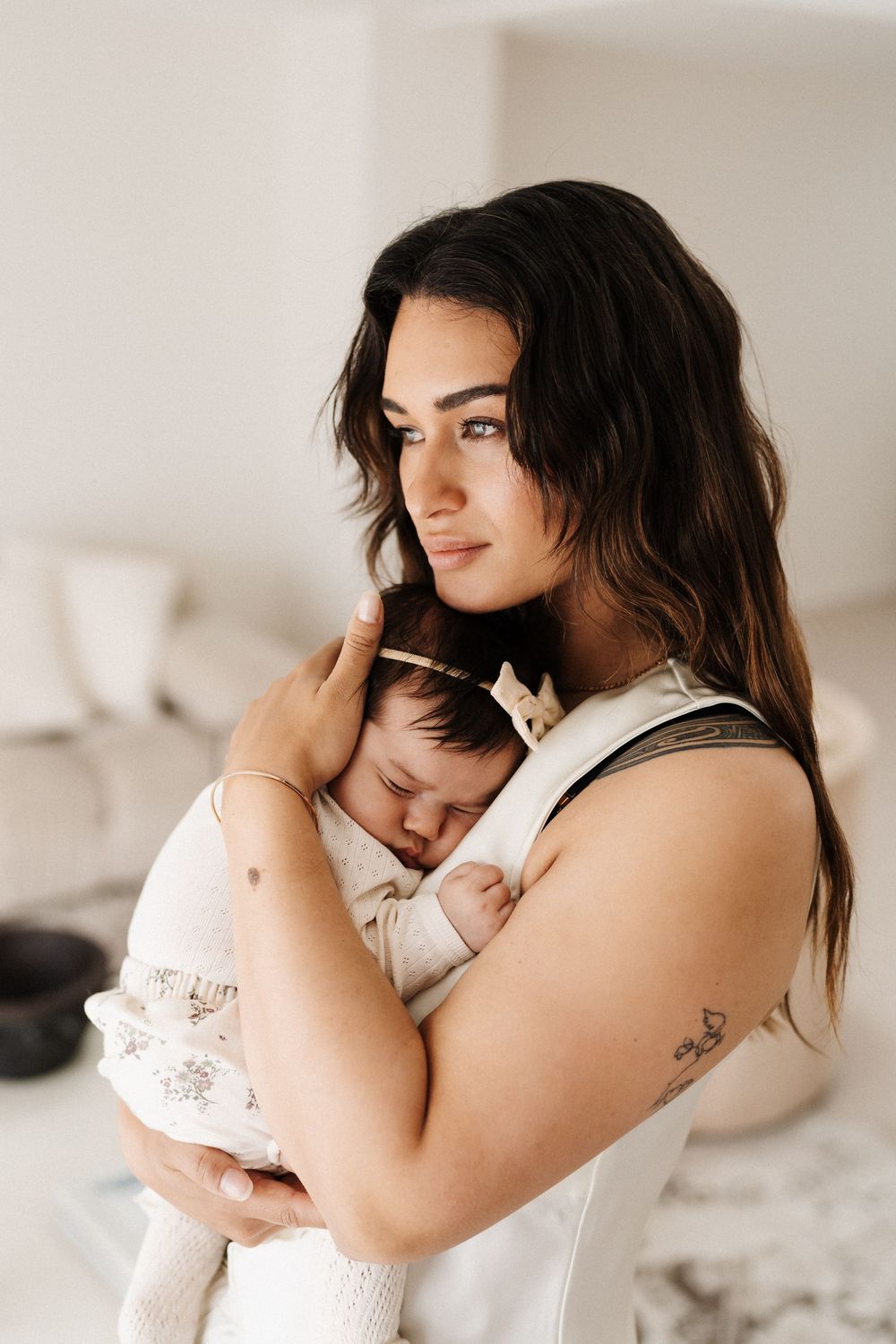 Close-up portrait of parent tenderly holding sleeping infant against white background.
