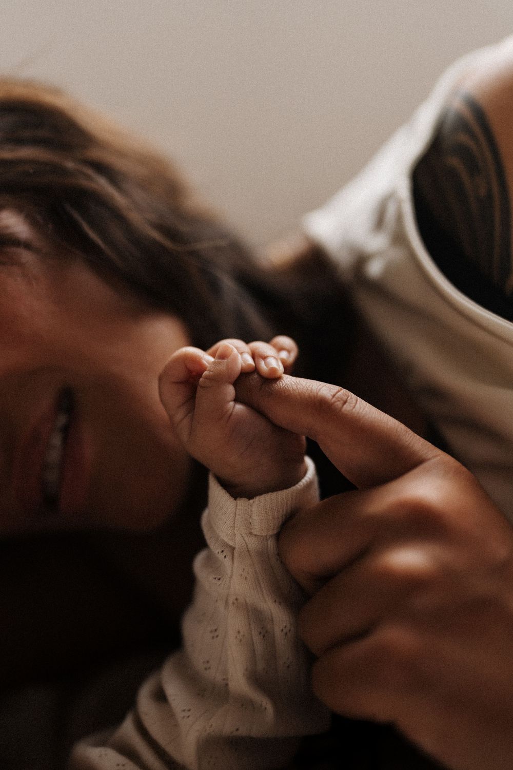 Close up artistic photo showing tender moment with small hand grasping finger in warm lighting.