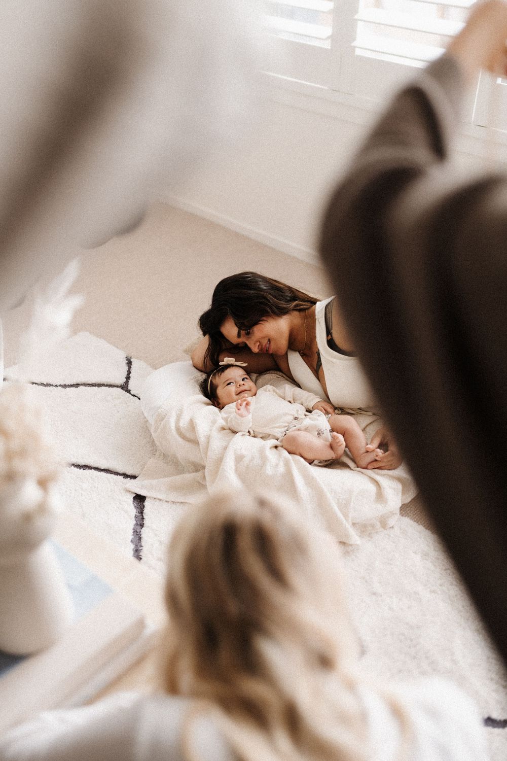 An intimate lifestyle photography session taking place on a white carpet in natural light.