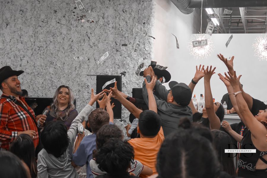 Crowd of people reaching up excitedly with raised hands at indoor event.