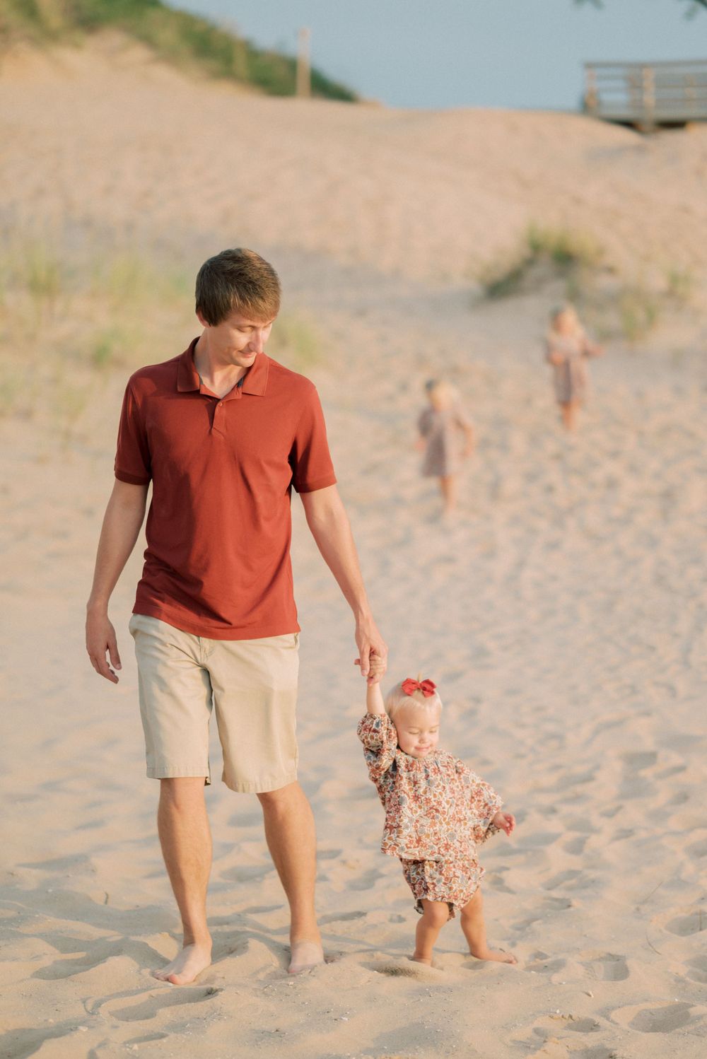 People walking together on sandy beach dunes during golden hour.