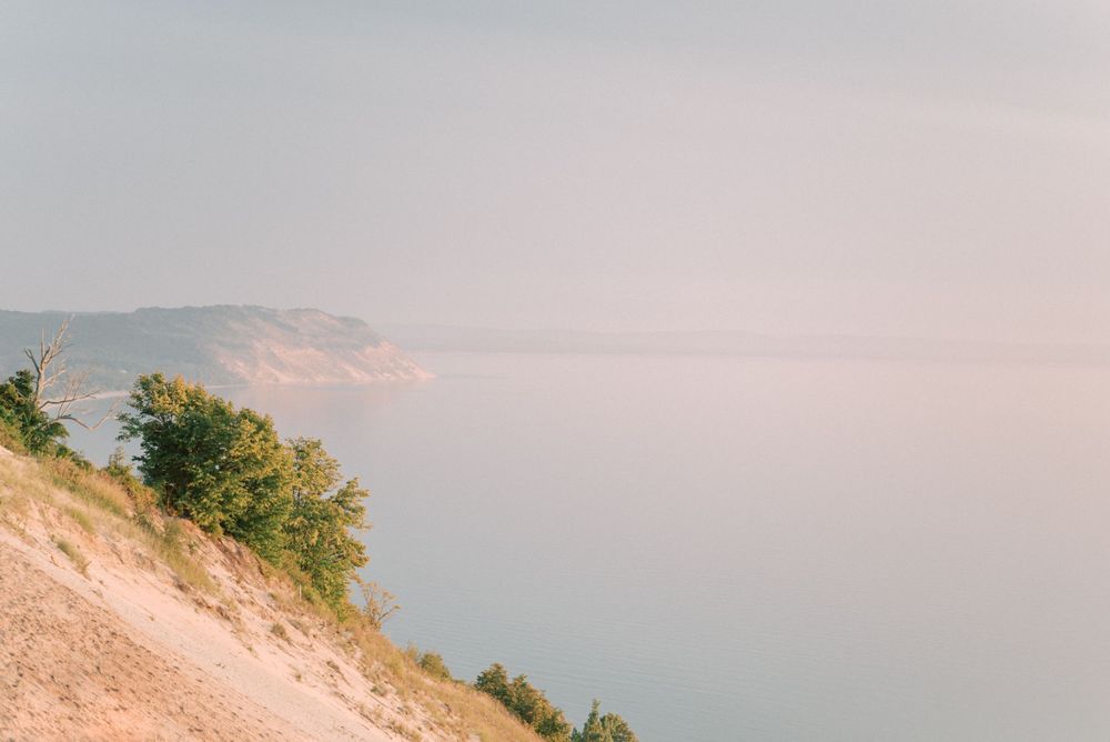 Scenic coastal landscape with sandy dunes and distant cliffs at sunset.