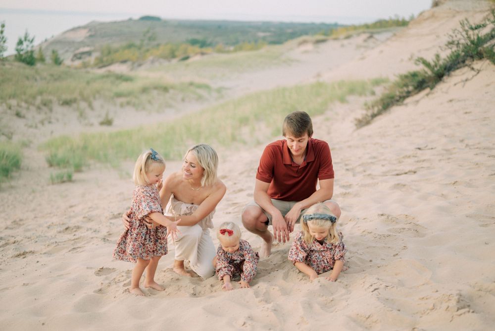 Family gathered together on sandy slope during outdoor photo session.