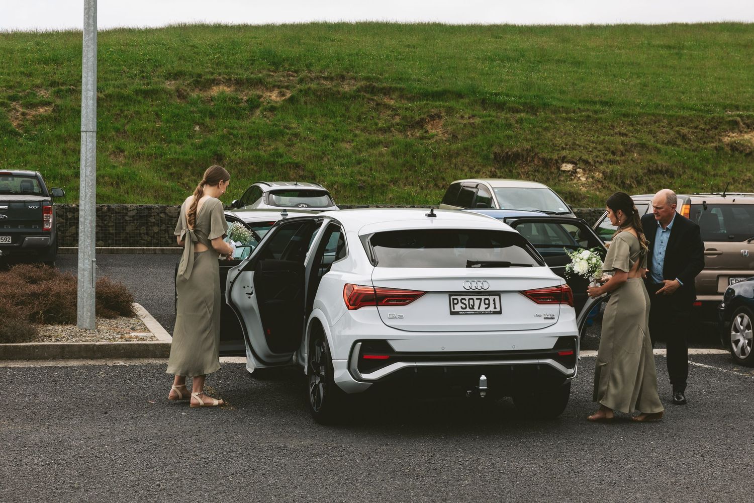 White Audi Q3 vehicle parked in outdoor parking lot with scenic mountain backdrop.